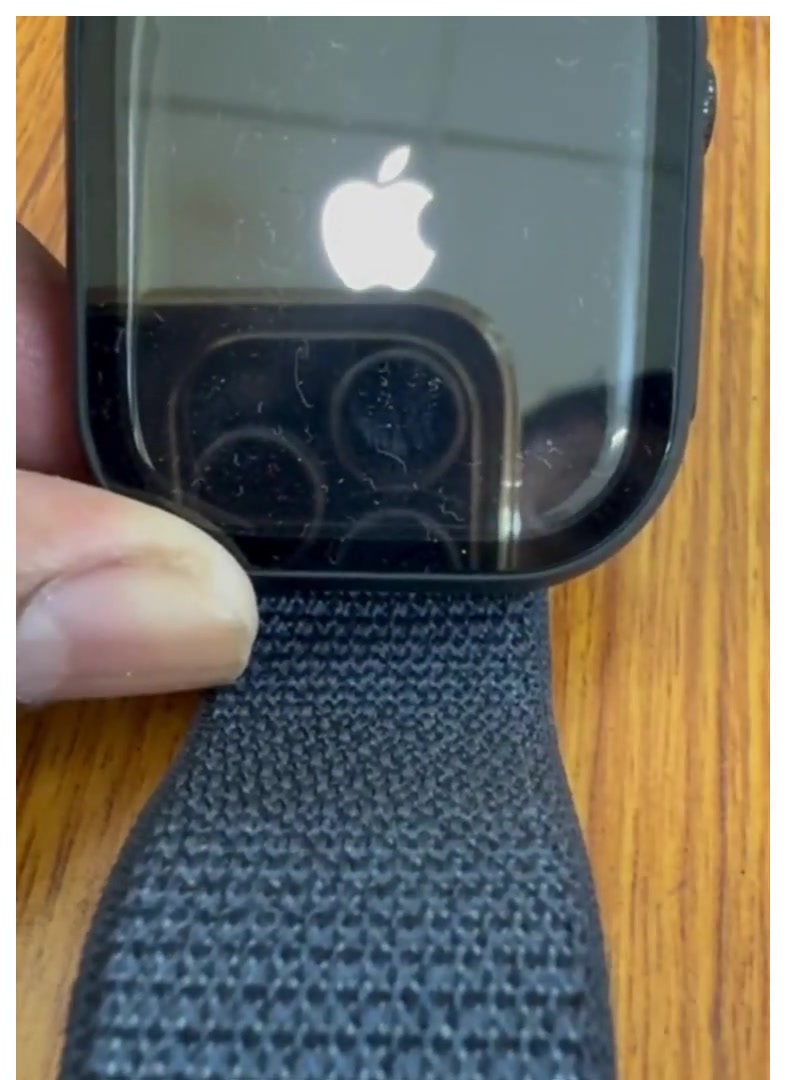 Apple Watch held in a hand showing the white Apple logo on a black screen