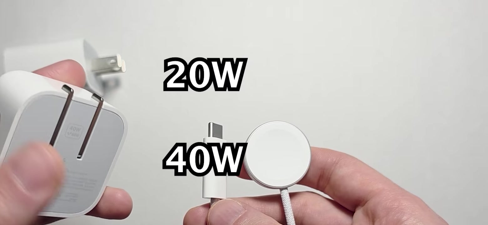 Hands holding a white Apple USB-C power adapter next to the Apple Watch charging cable, with 20W and 40W labels on screen