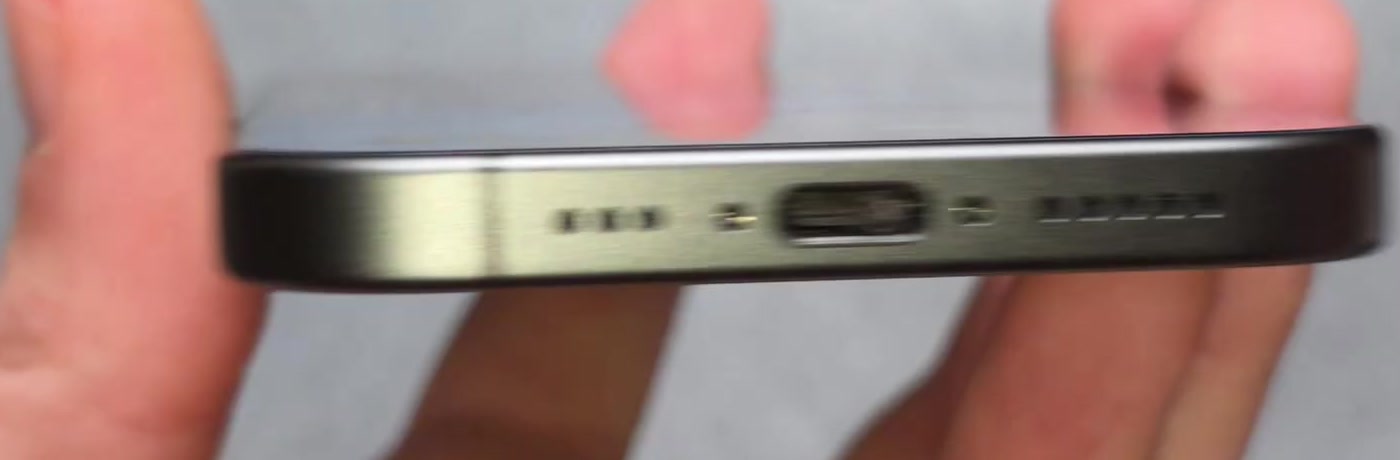 Close-up of the USB-C charging port on the bottom edge of an iPhone, between the speaker grilles