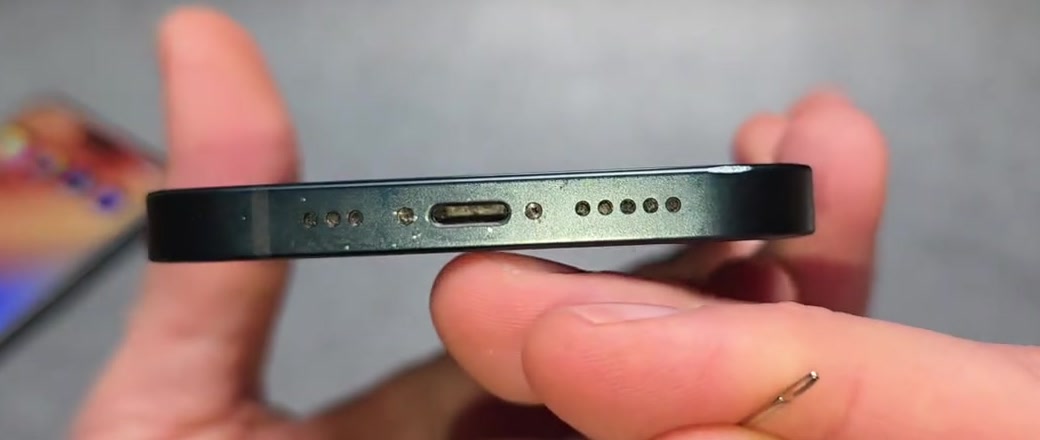 An iPhone held sideways under a light with the USB-C charging port visible after cleaning
