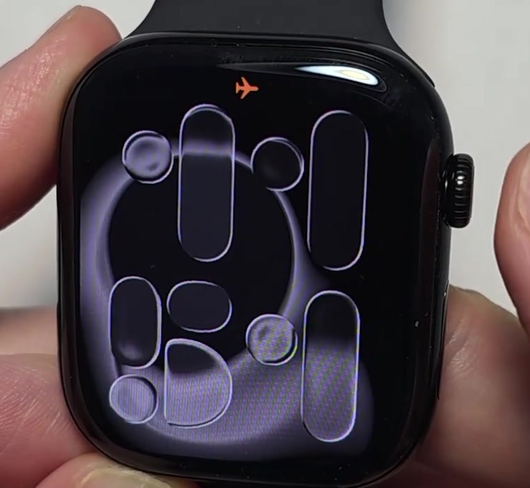 Apple Watch face with a small orange airplane icon in the status area at the top of the screen