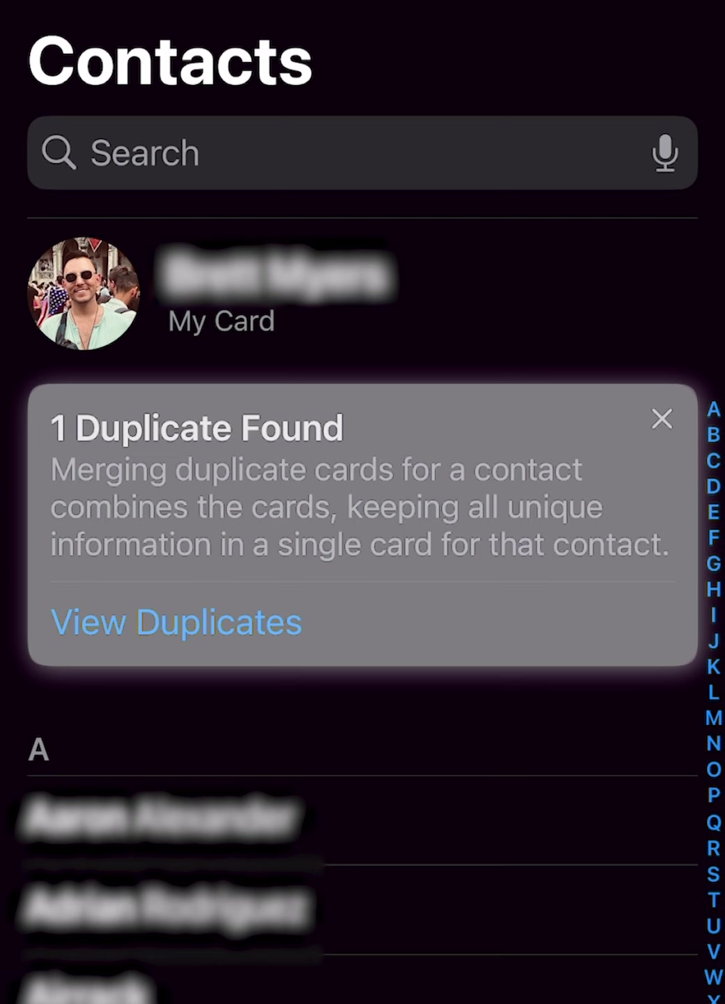 iPhone Contacts list showing a Duplicate Found banner under My Card with a View Duplicates link