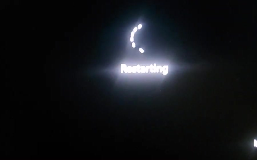 A dark laptop screen showing a spinner and the word Restarting