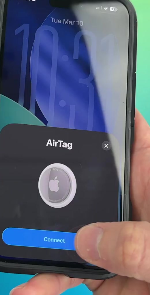 A hand holding an AirTag beside an iPhone showing the AirTag pairing card with the Connect button highlighted