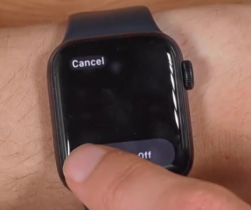 A finger dragging the Power Off slider to the right on an Apple Watch
