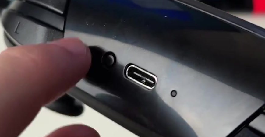 Top edge of a Nintendo Switch Pro Controller showing the small round SYNC button next to the USB-C charging port